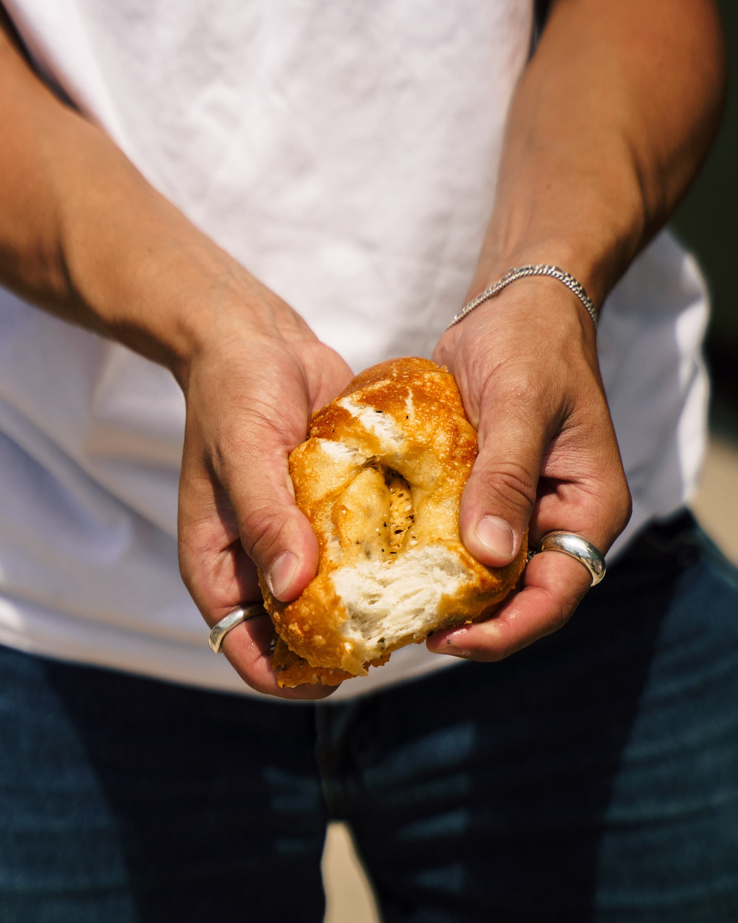 A fresh bagel being pulled apart by hand