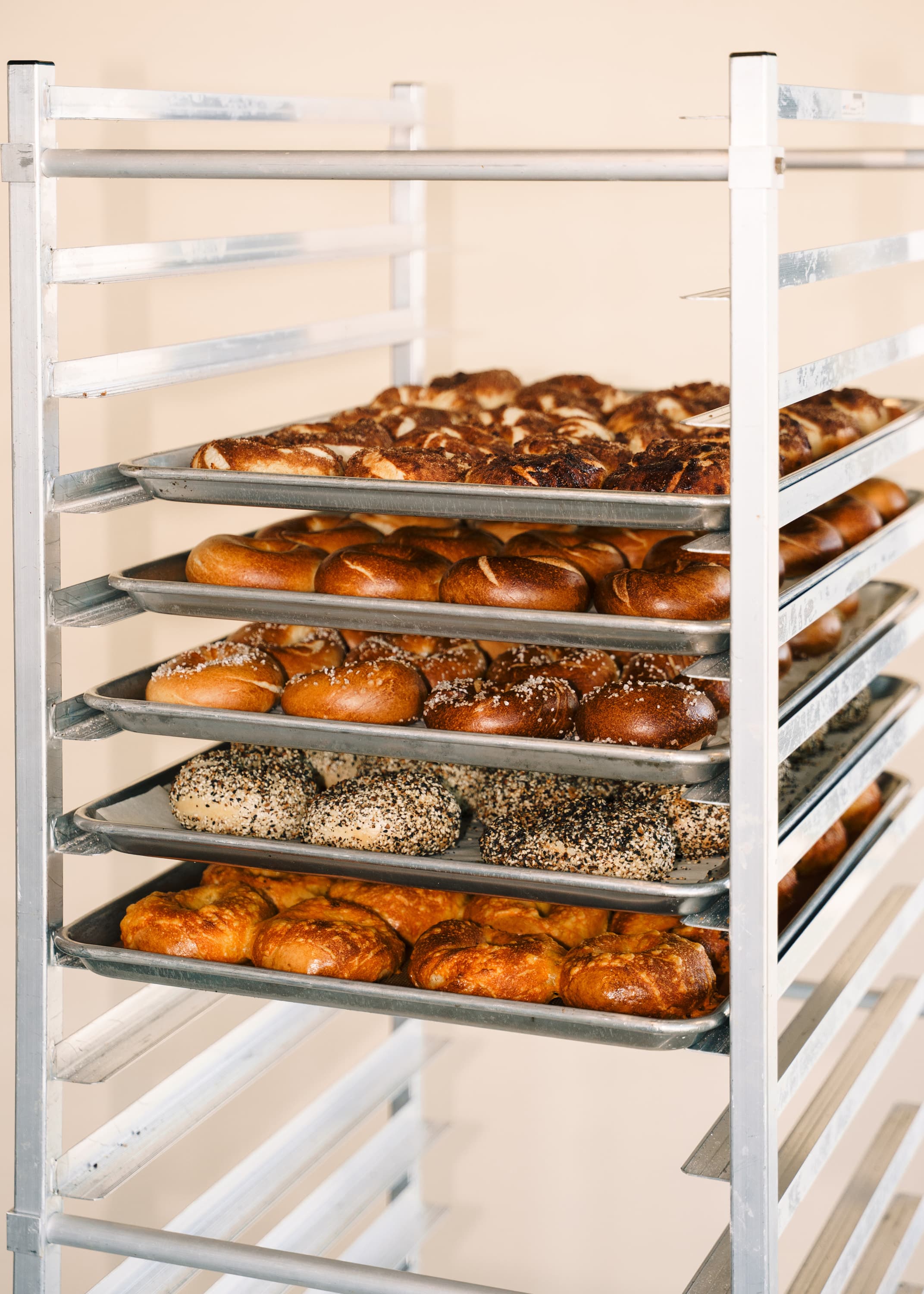 A bakery rack filled with trays of fresh bagels