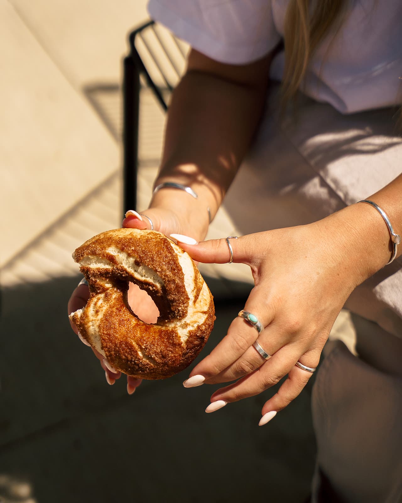 A cinnamon bagel being pulled apart by hand