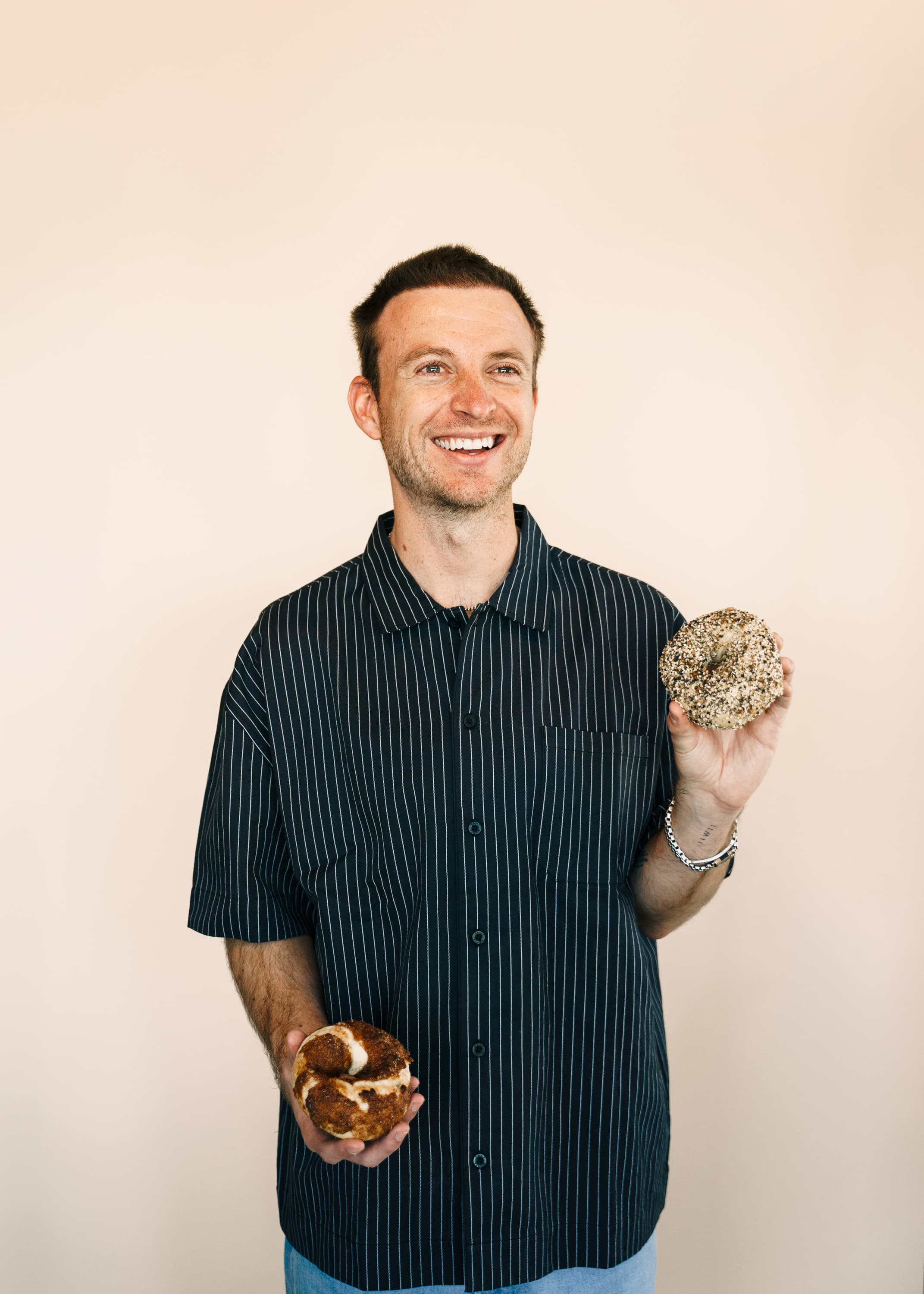 The founder of Oh No Bagels holding two fresh bagels